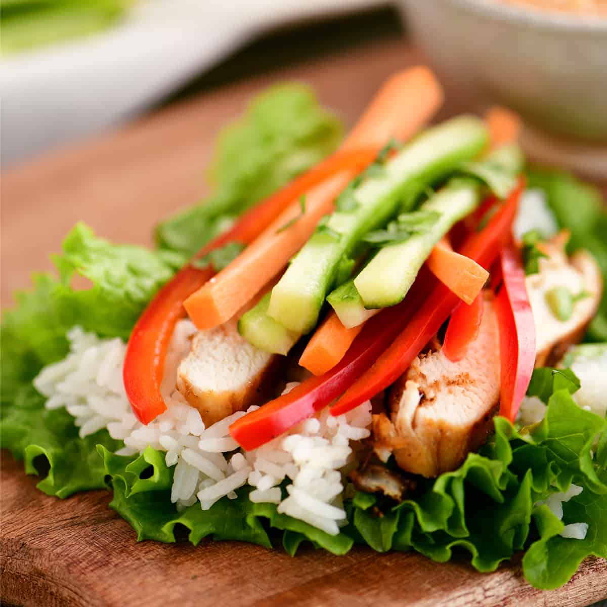 Lettuce leaf with chicken, rice, and veggies on top.