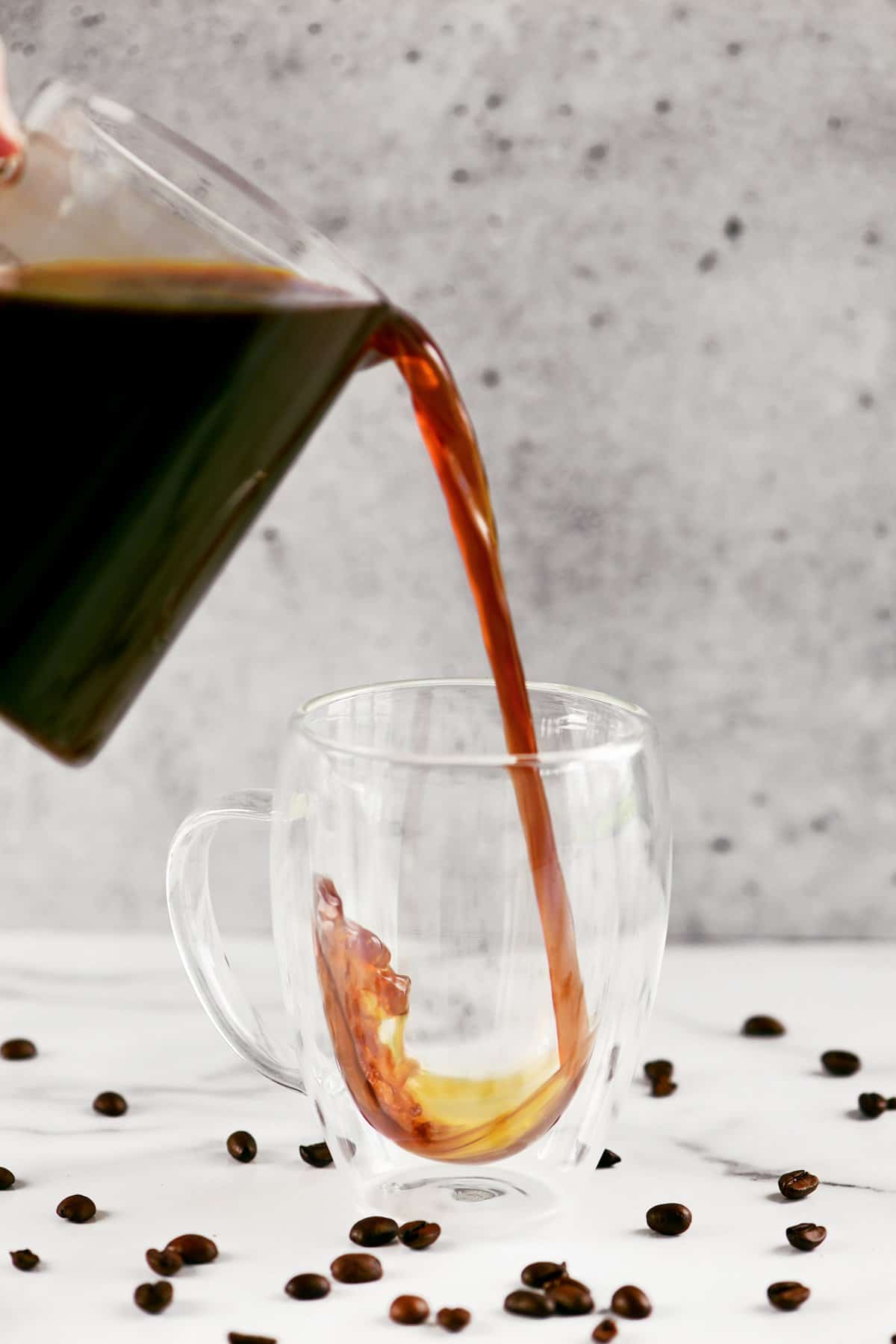 a hand pouring cold brew into a cup