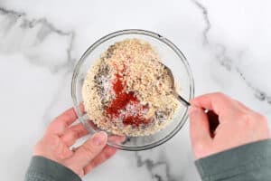 hands stirring spices and breadcrumbs with a spoon