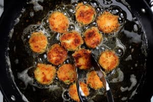 frying breaded summer squash slices in a pan