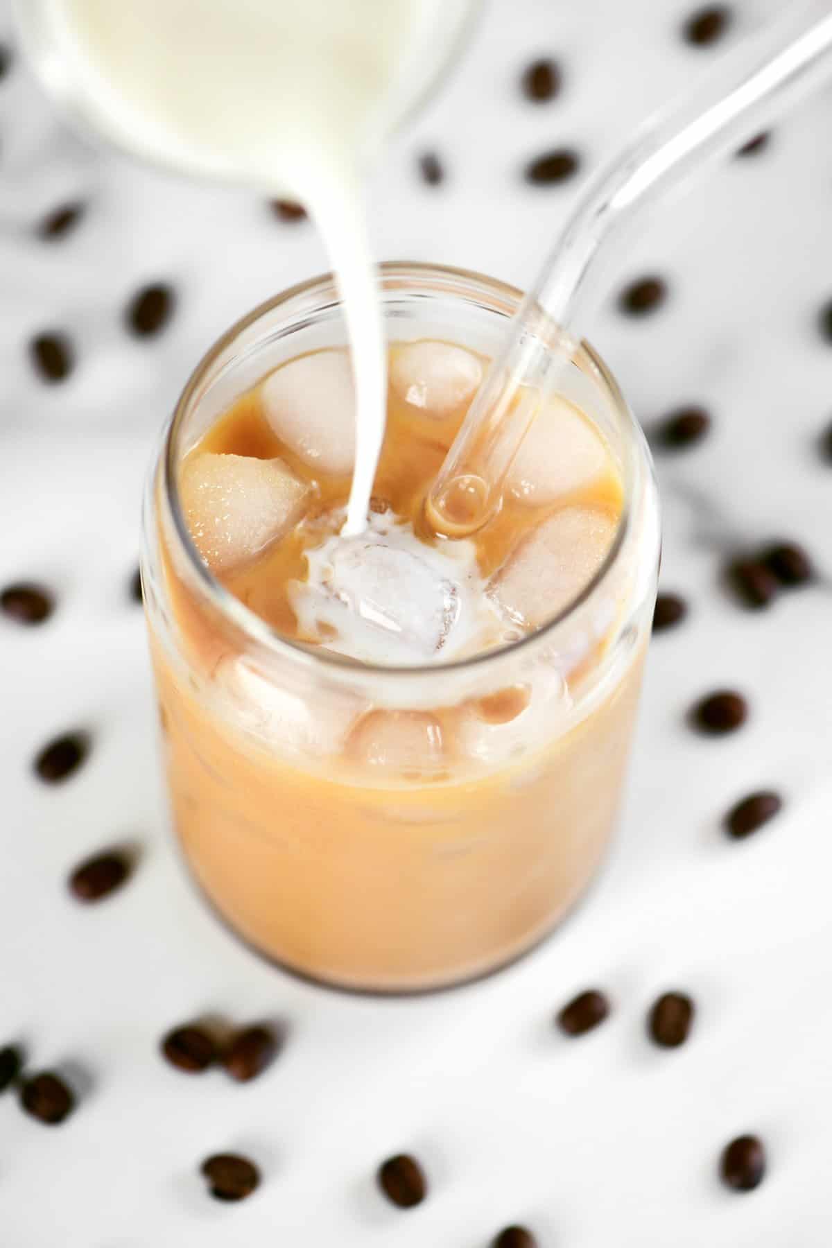 pouring half and half into iced coffee