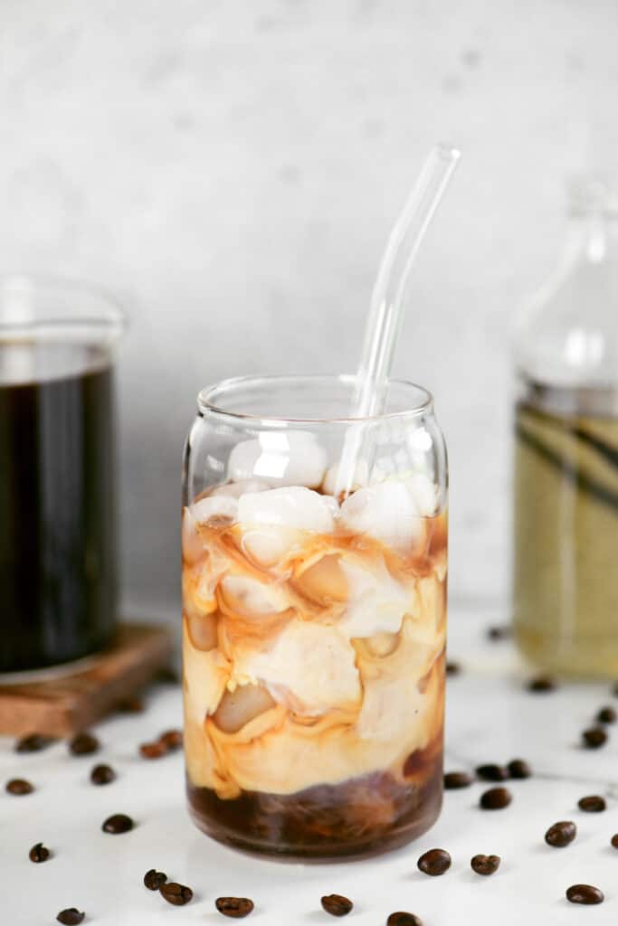 cold brew with ice and half and half in a glass with a glass straw