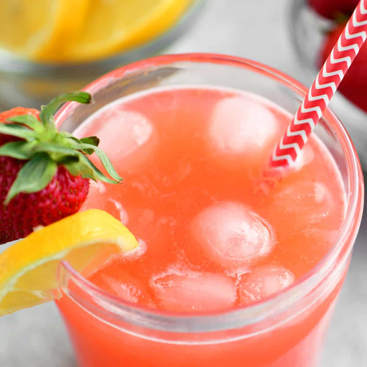 strawberry lemonade in a glass with a red and white striped straw