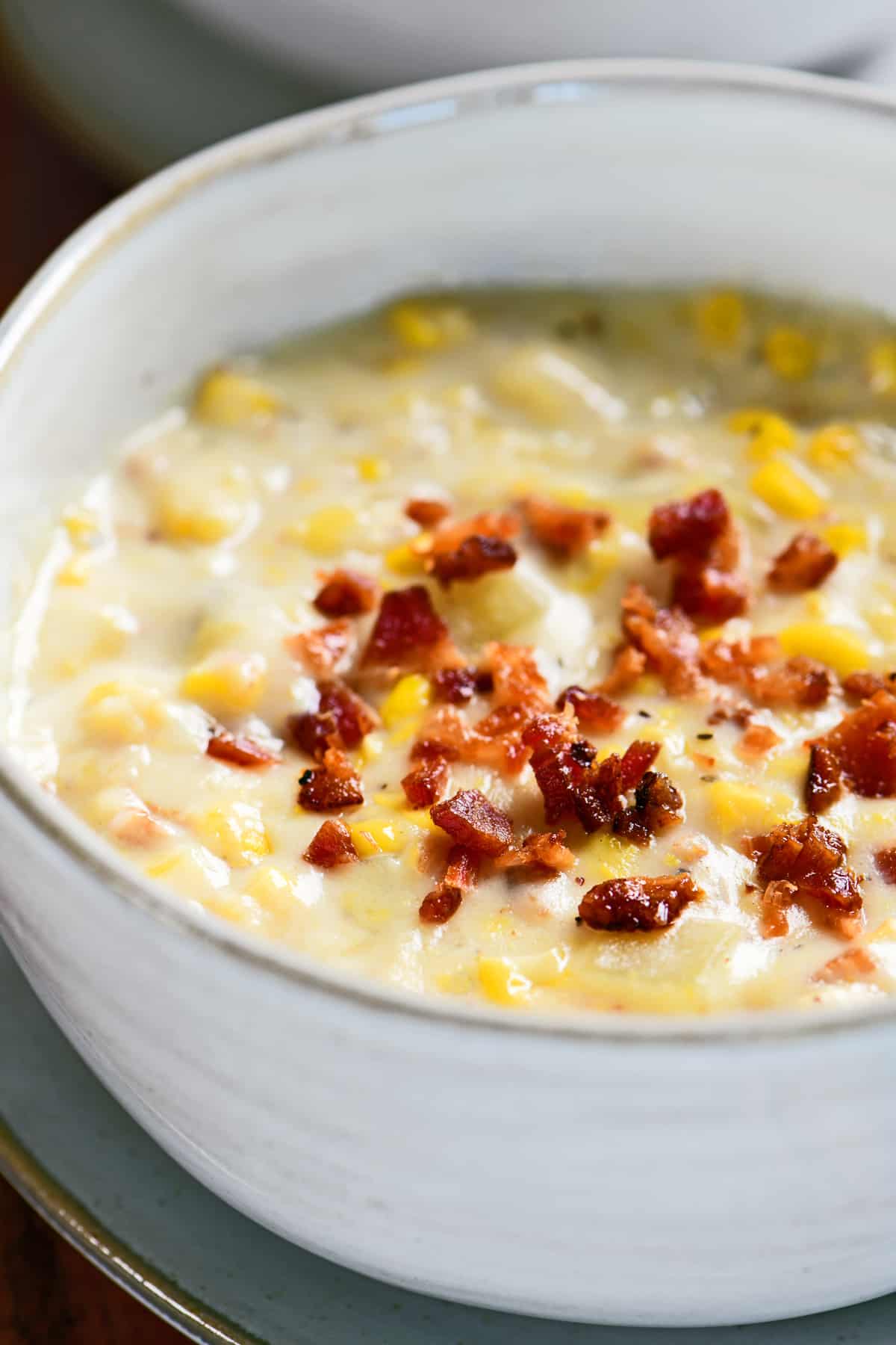 corn chowder with bacon crumbles in a white bowl.