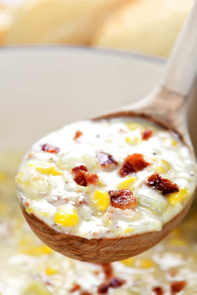 a wooden spoon with corn chowder inside.