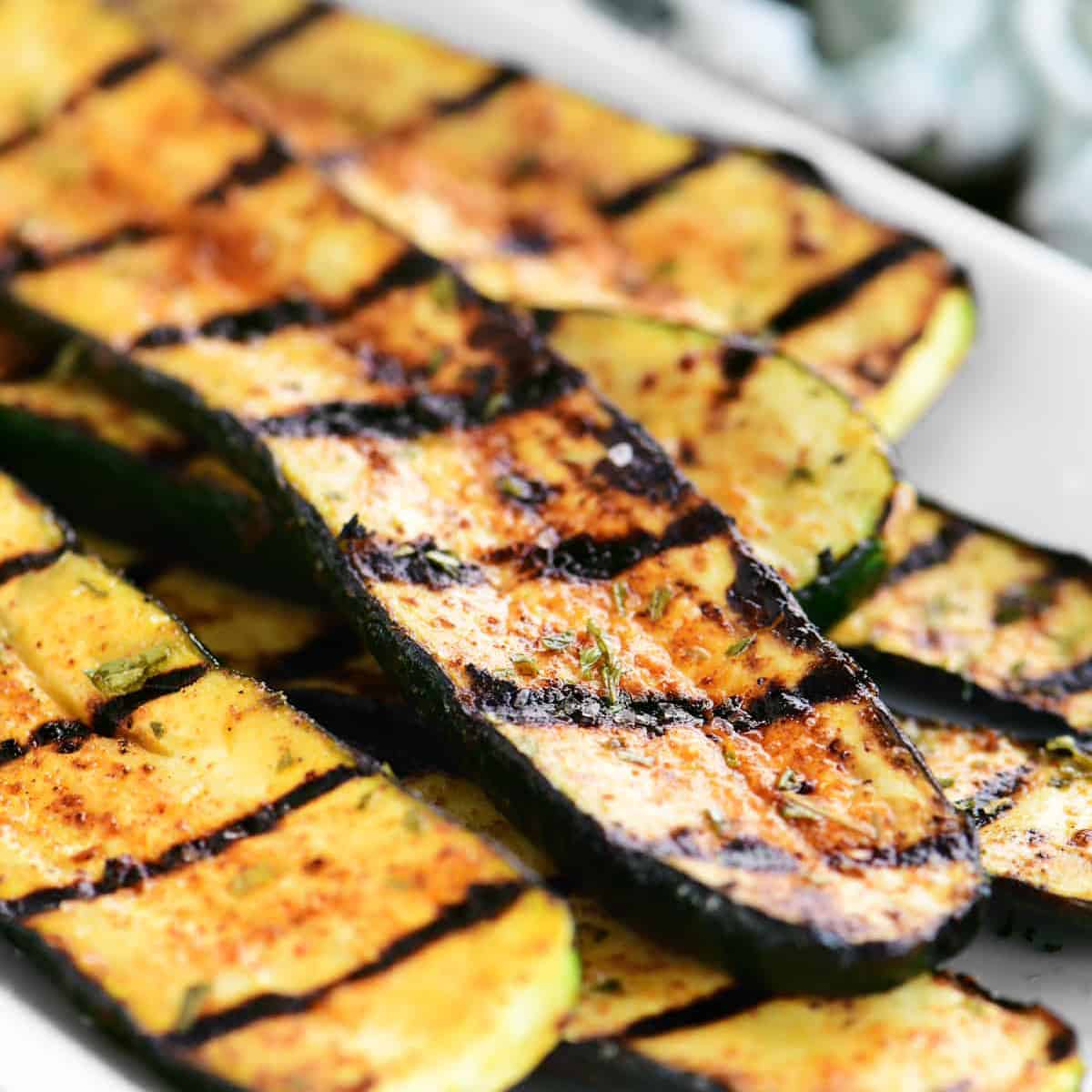 stack of grilled zucchini on a white platter.