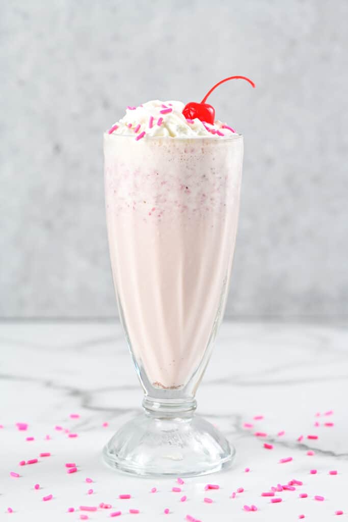 a strawberry milkshake in a glass.