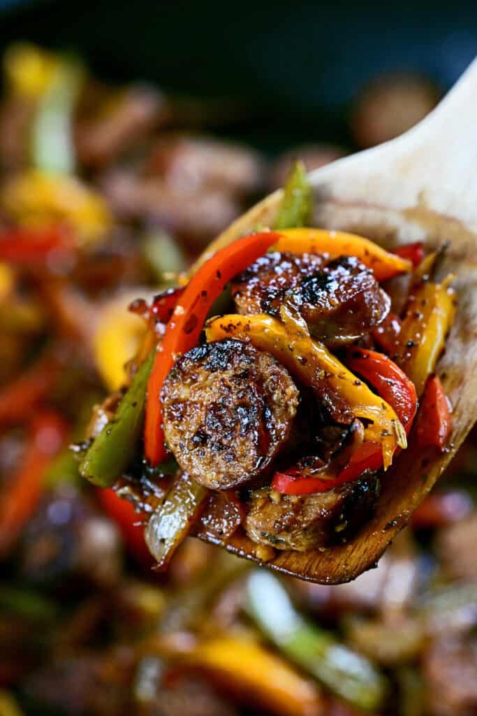 sausage and peppers on a wooden spoon.