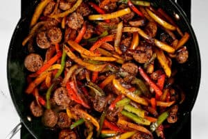 meat and vegetables frying in a pan.