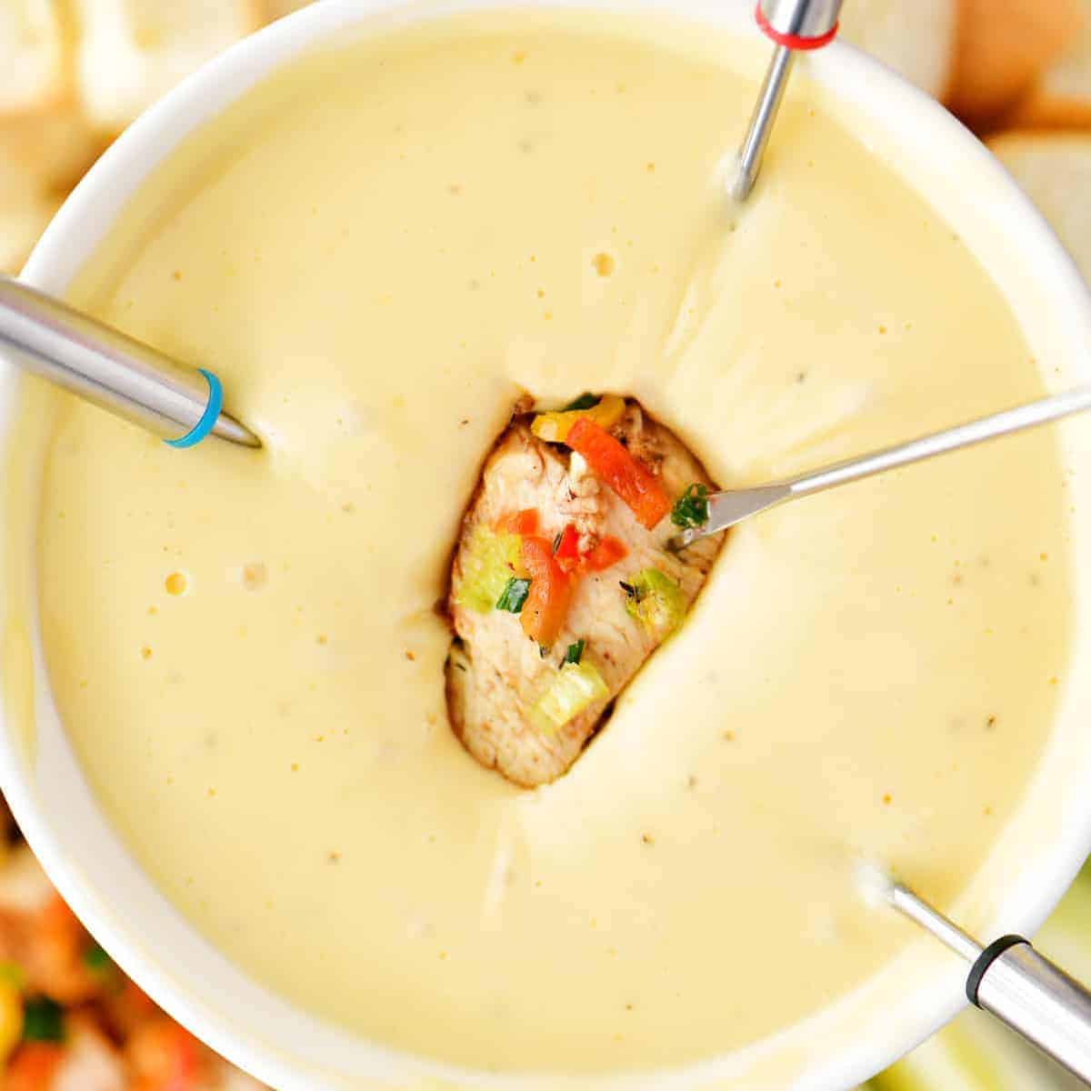 a piece of chicken being dipped into smoked gouda fondue.