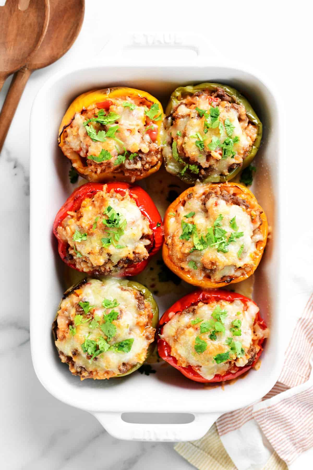 eight stuffed peppers in a white casserole dish.