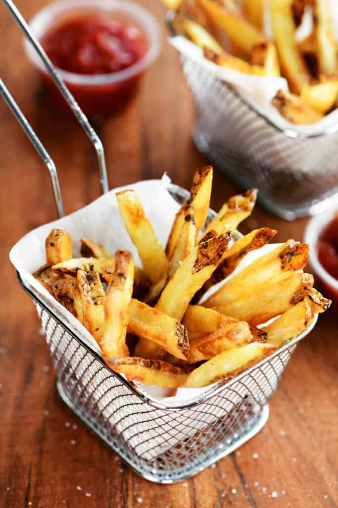 golden brown French fries in a parchment lined mini wire fry basket.