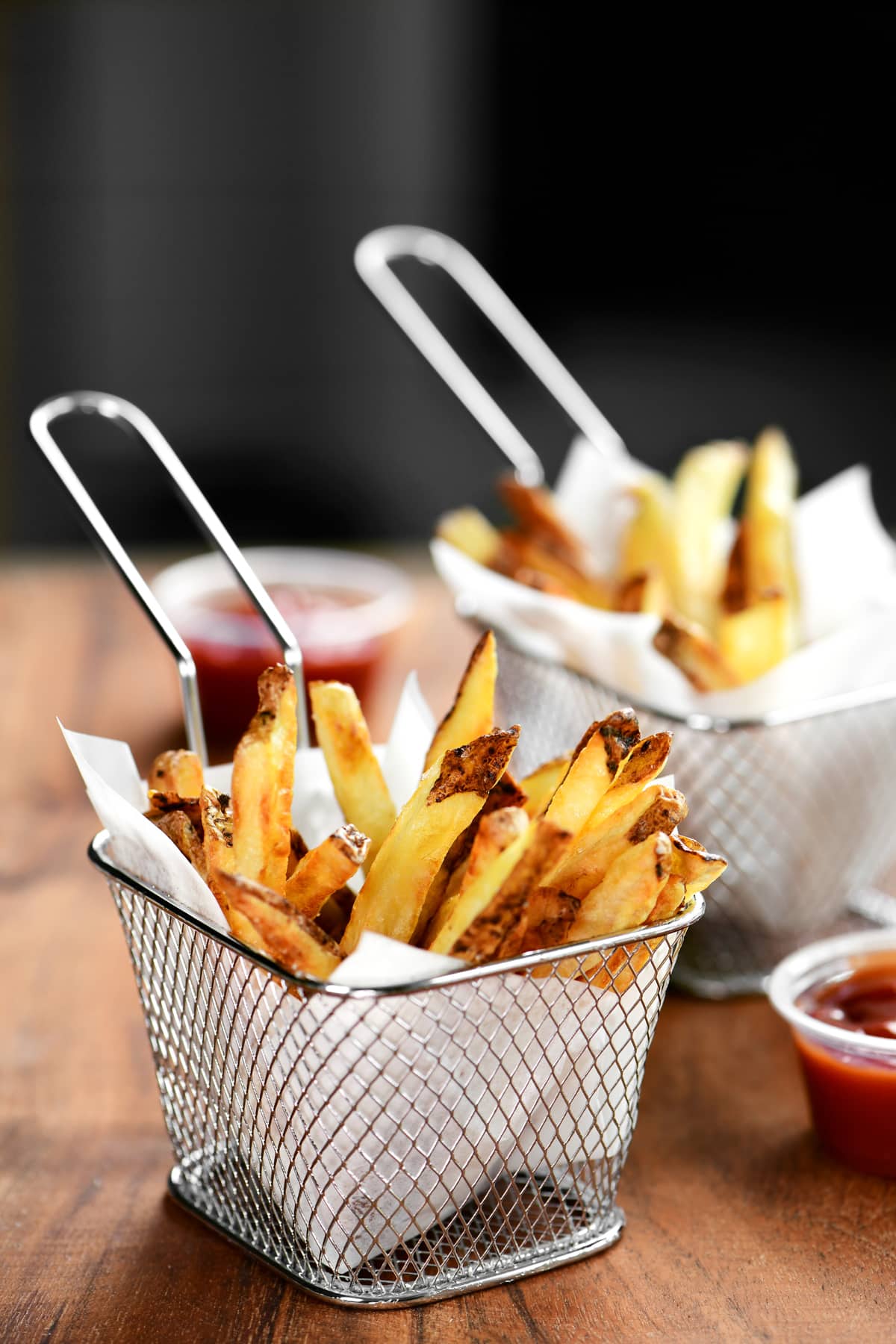 two wire fry baskets holding crispy air fryer french fries.