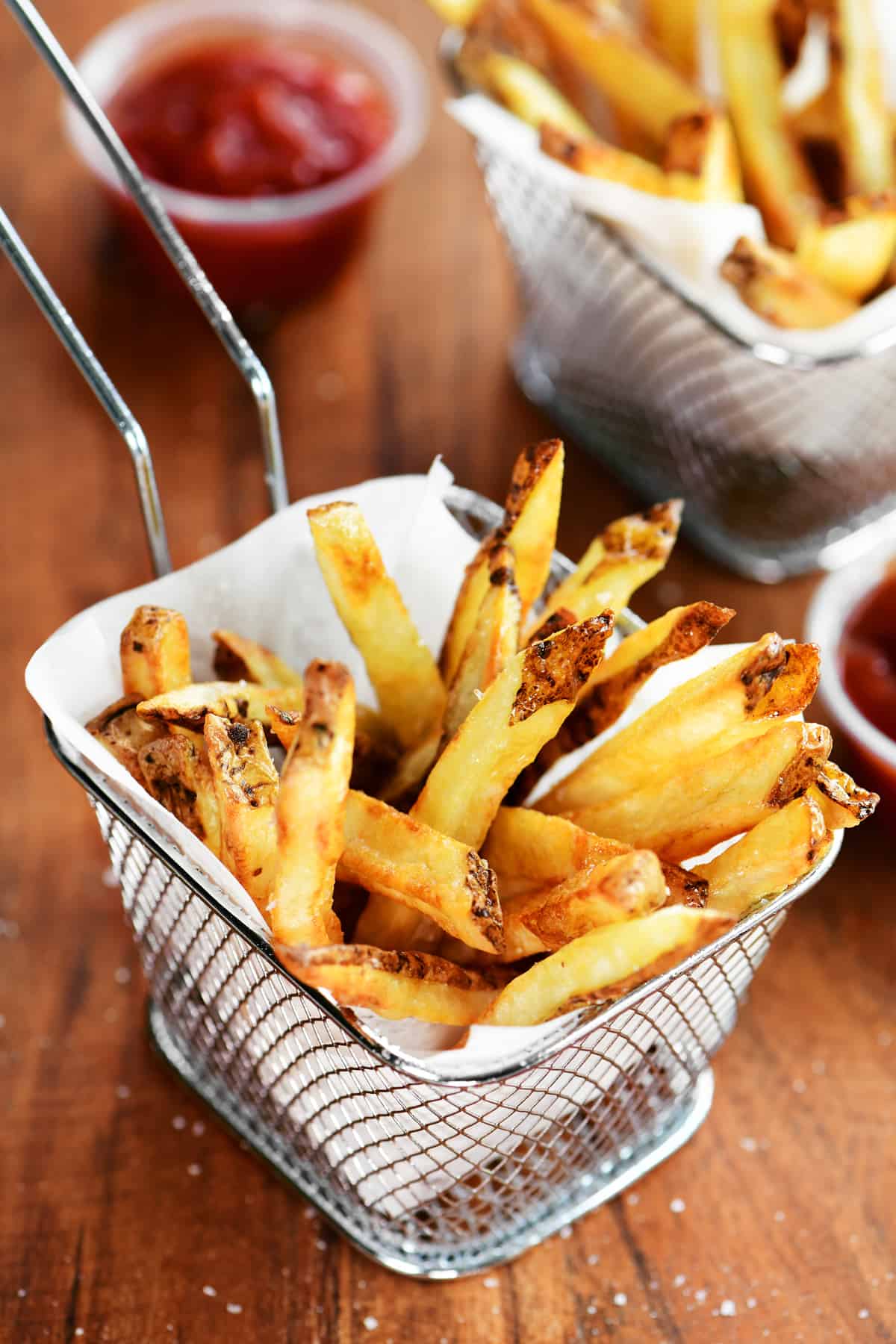 golden brown French fries in a parchment lined mini wire fry basket.