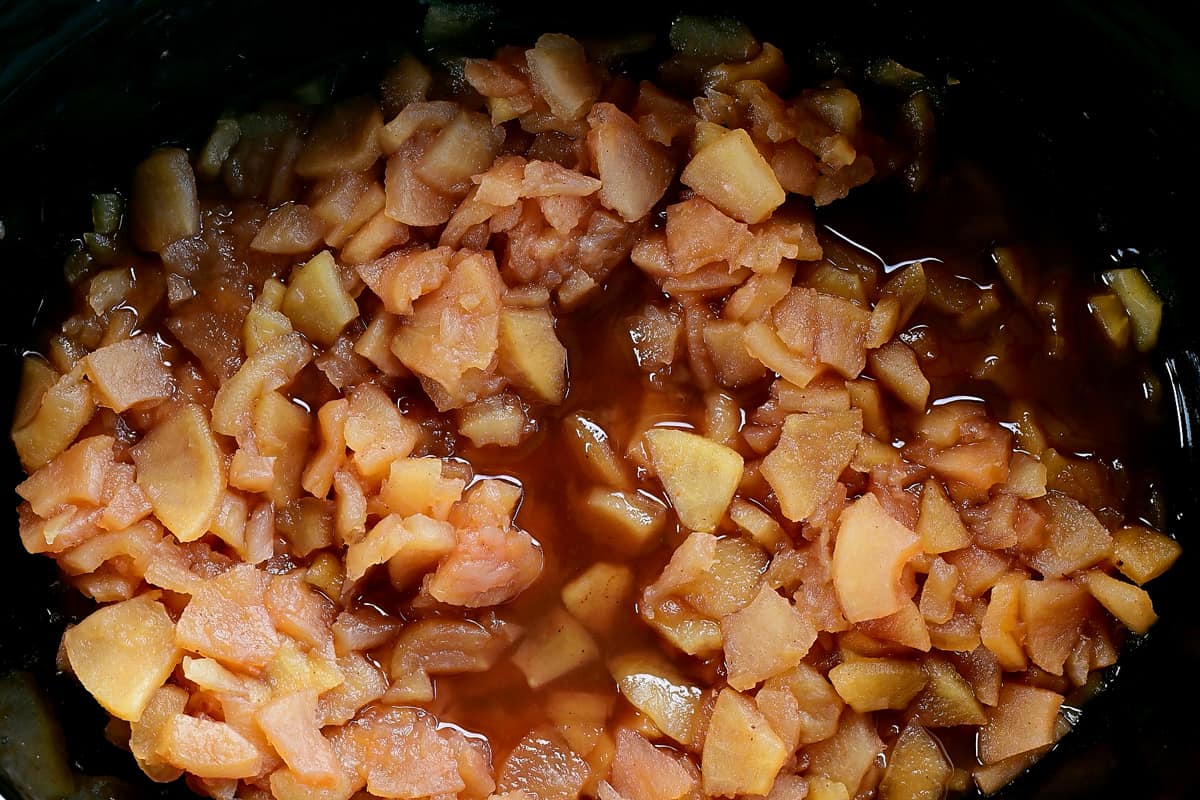 sliced cooked apples cooling in a crock pot.