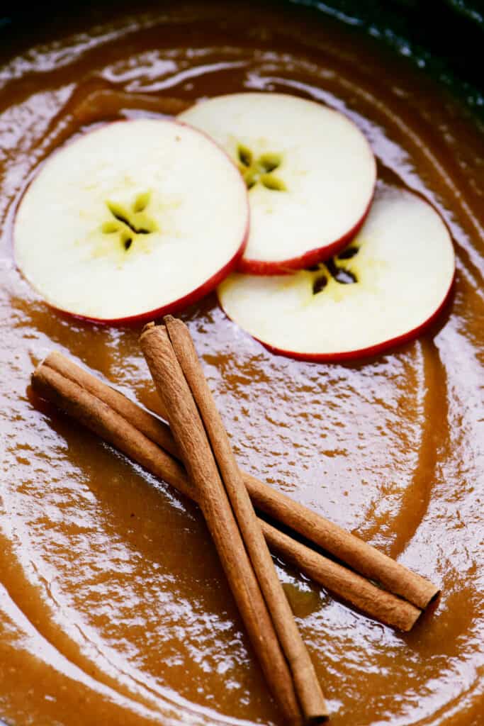 cinnamon sticks and apple slices on applesauce in a crock pot.