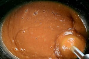 an immersion blender pureeing applesauce in a crock pot.