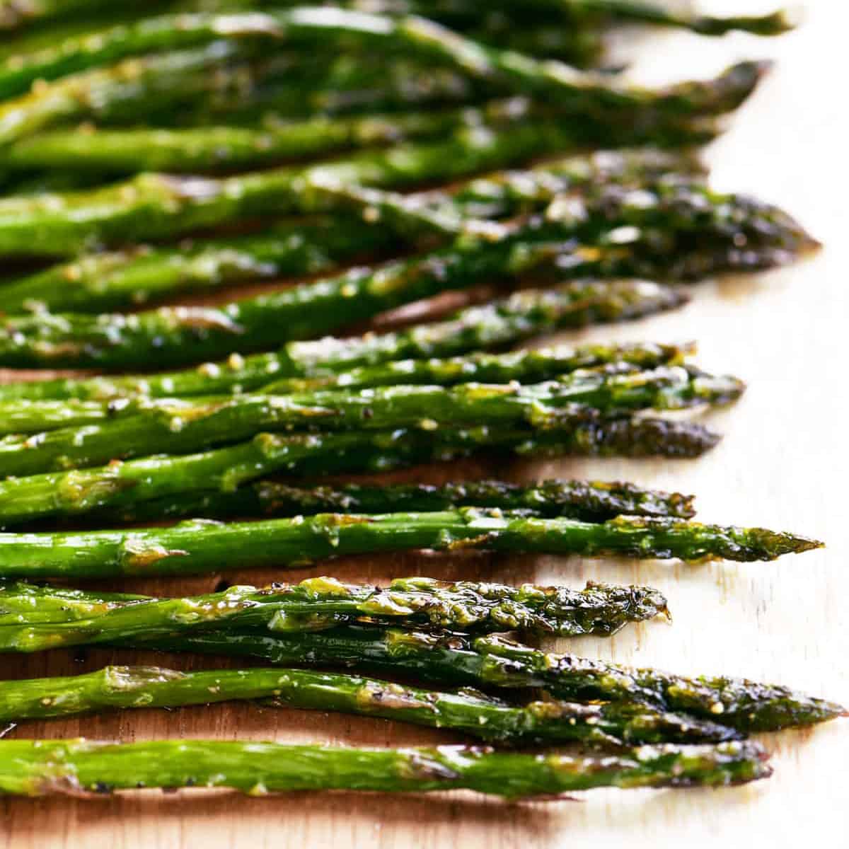 rows of roasted asparagus on a wooden platter.