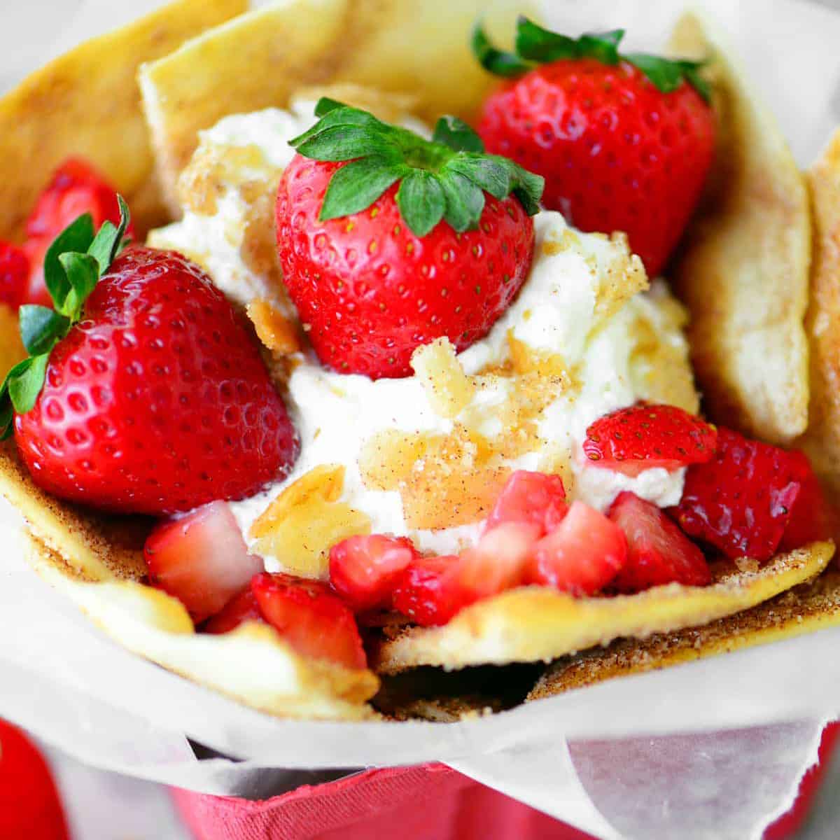 strawberries, whipped cream, and cinnamon chips in a red berry basket.