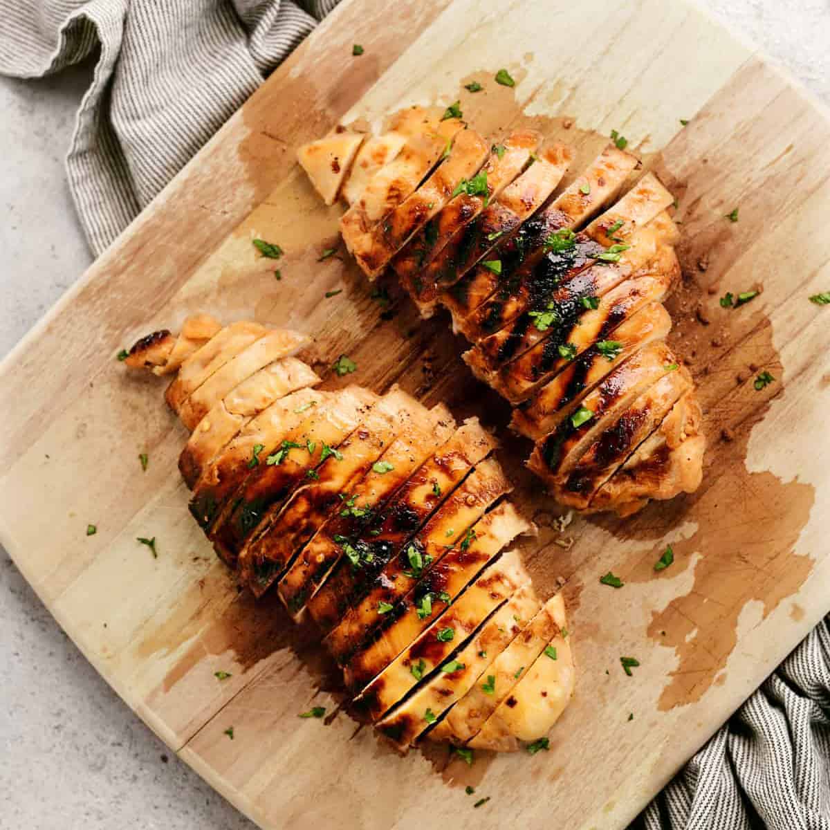 sliced chicken breasts on a wood cutting board.
