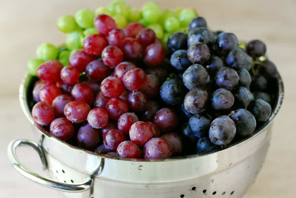 colander filled with red, black, and green grapes.