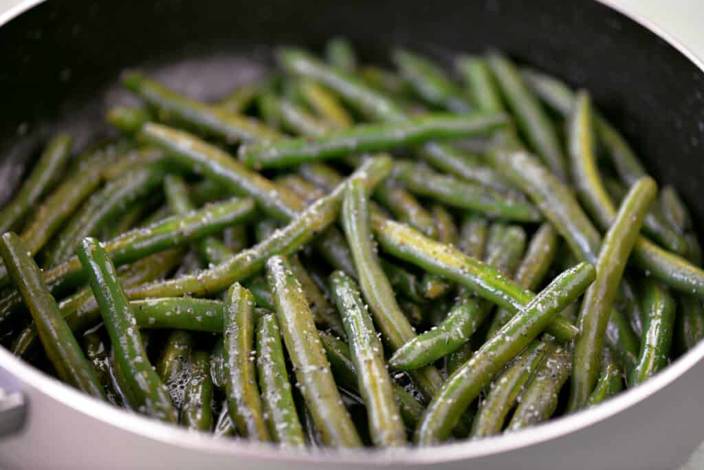 fresh green beans in a saute pan with bacon grease