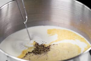 a whisk stirring seasoning into a pot of milk.