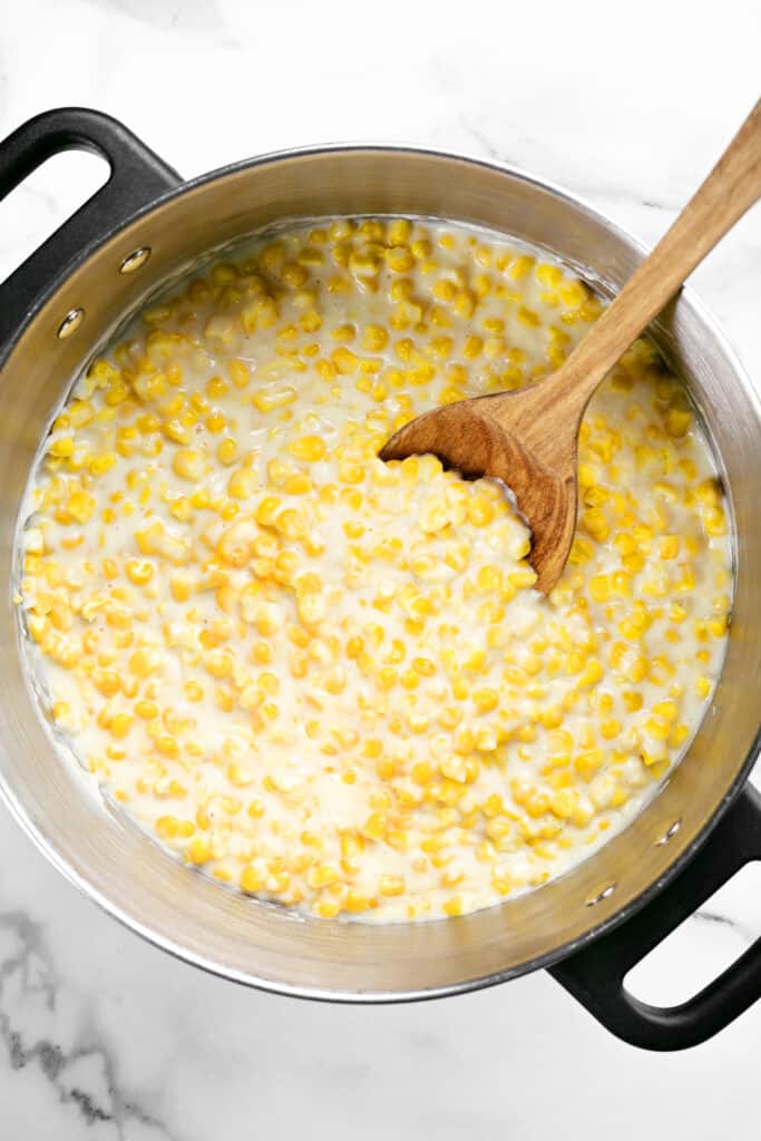 a pot of corn with a wooden spoon inside.