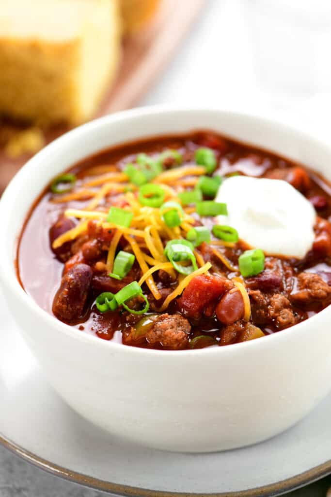 a white bowl of crock pot chili with toppings.