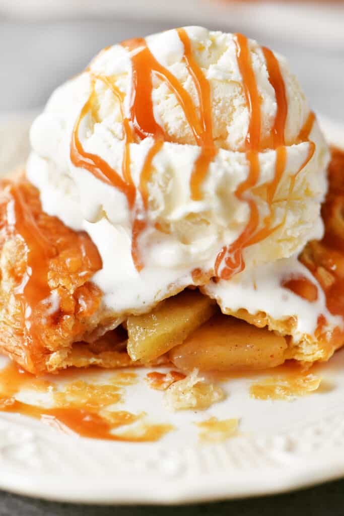 mini apple pie on a white plate with ice cream on top.