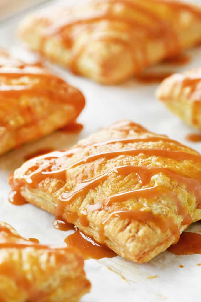 mini apple pies with caramel drizzled on top.