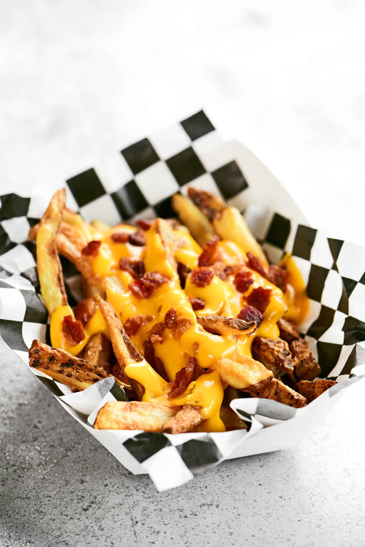 melted cheese and bacon bits on top of french fries.