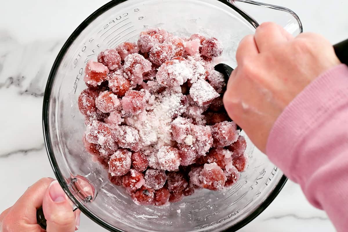 mixing cherries, sugar, and tapioca in a glass batter bowl.