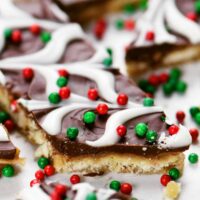 close up showing the layers of christmas crack saltine cracker toffee with red and green decorations.