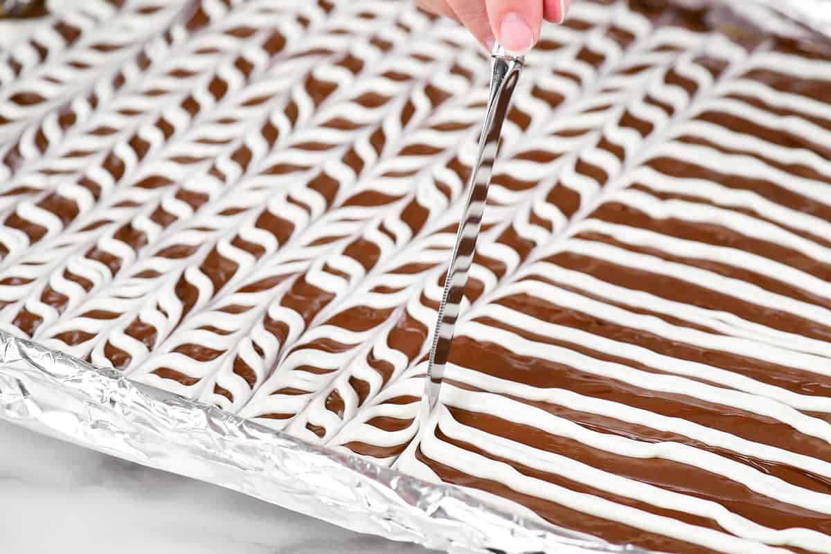 dragging a knife through the chocolate to create a pattern.