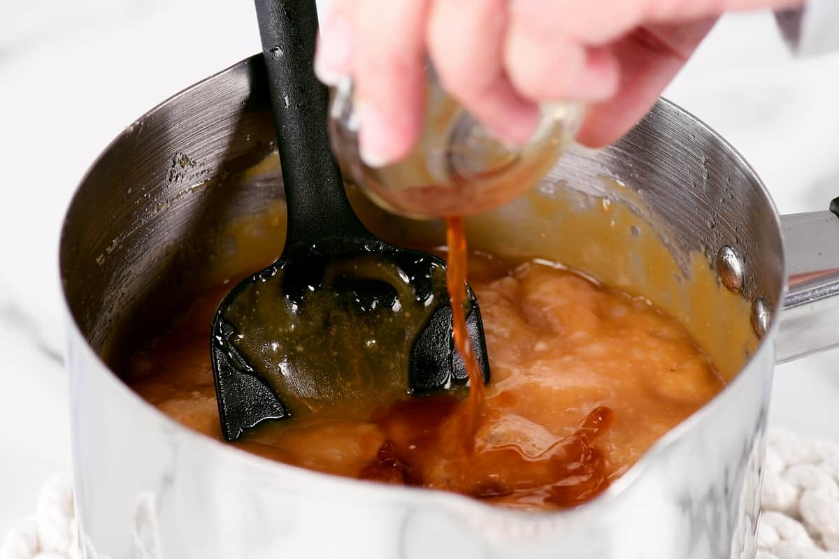 pouring vanilla extract into the hot caramel sauce.
