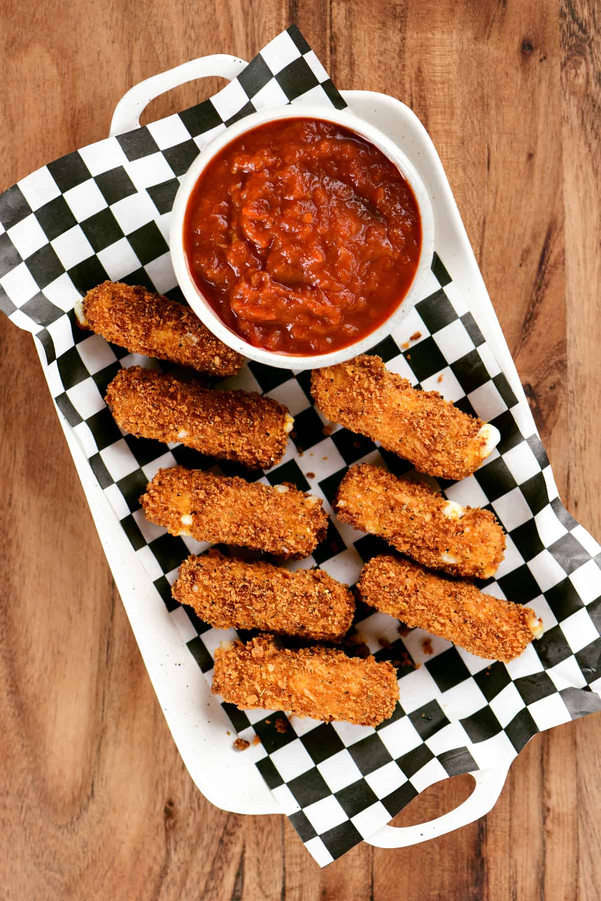 eight mozzarella sticks and some red sauce on a platter.