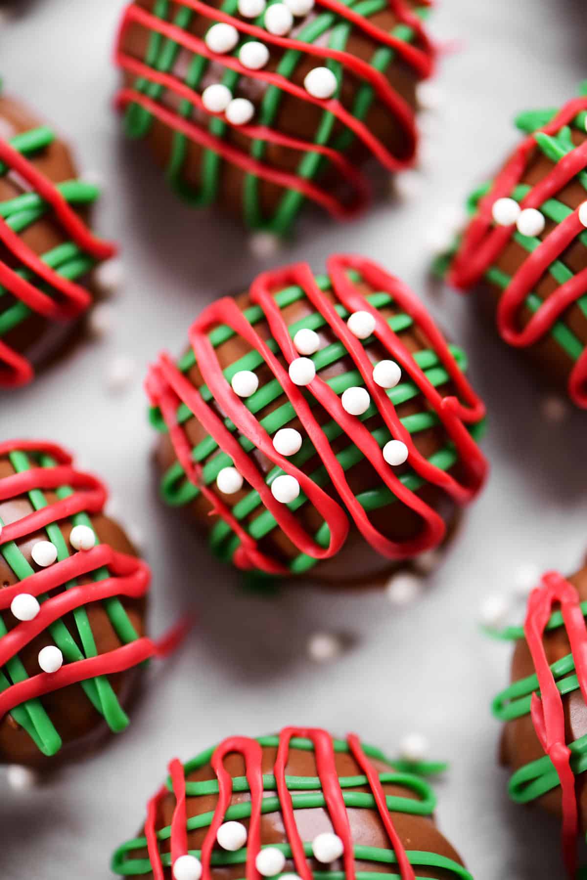 chocolate covered peanut butter balls with red and green drizzles on top.