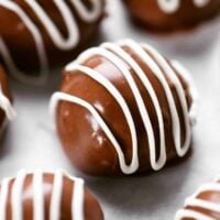 chocolate coated peanut butter balls with a white drizzle on top.