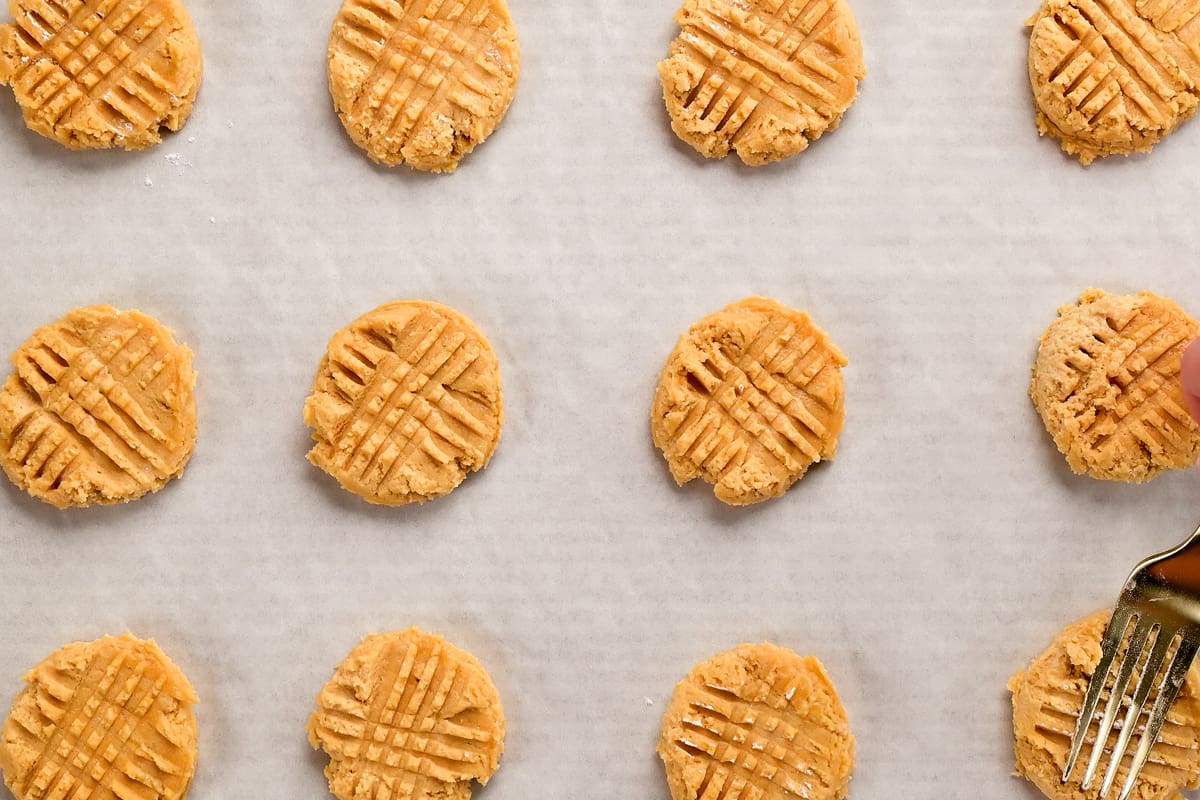 a fork making a crosshatch pattern in the cookie dough rounds.