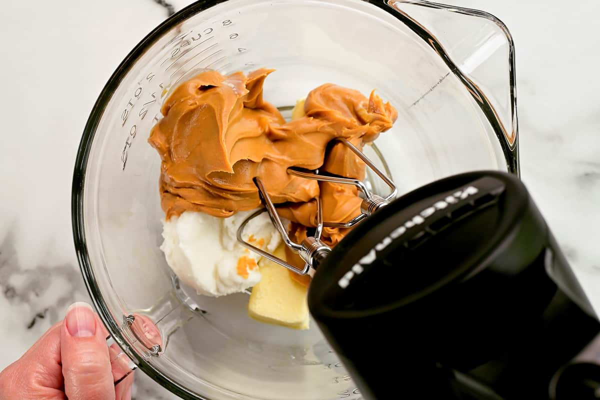 a hand mixer and cookie dough ingredients in a mixing bowl.