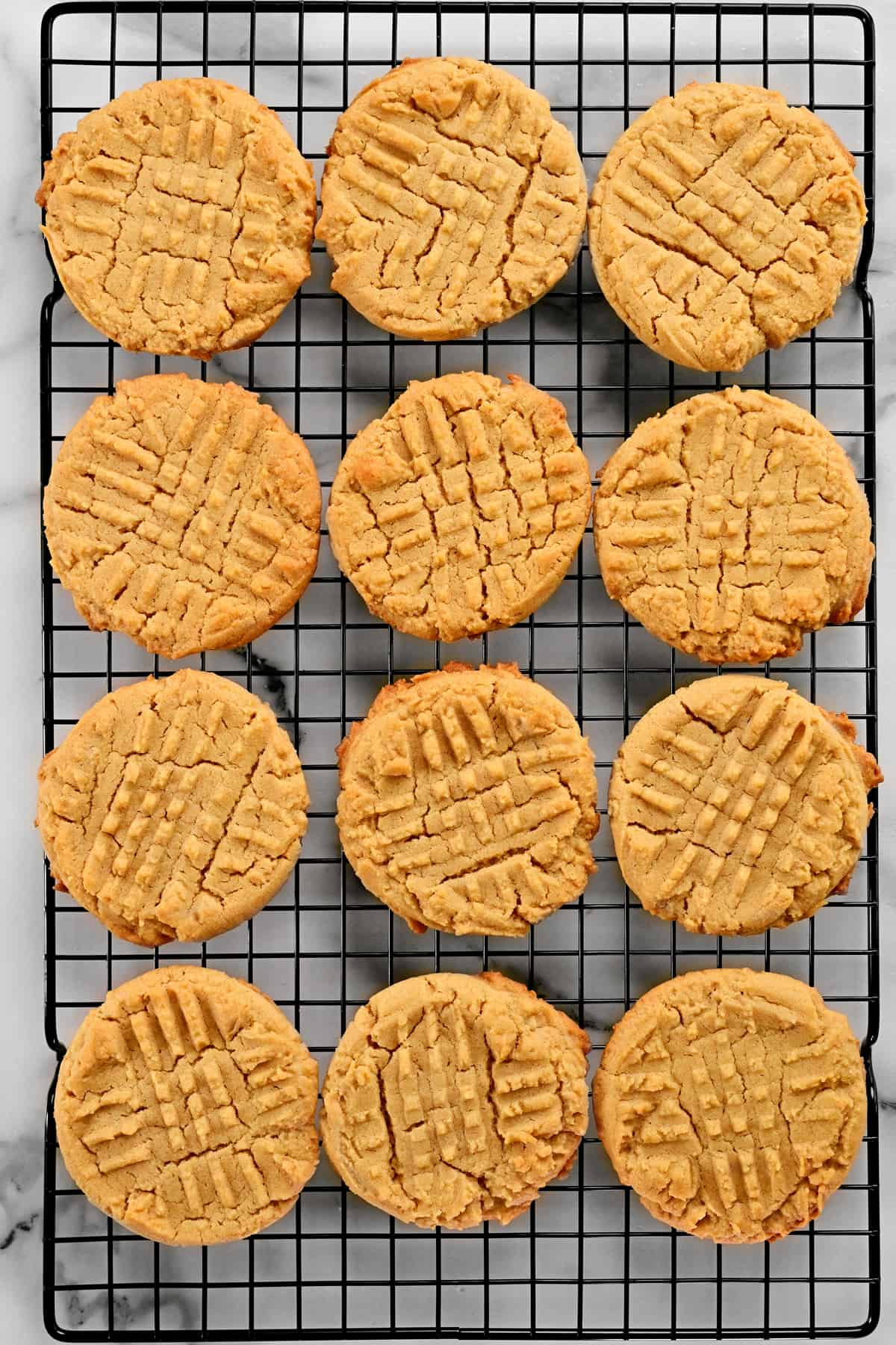 A dozen peanut butter cookies on a wire rack.