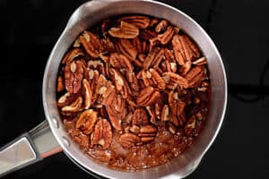 pecan halves added to syrup in saucepan.