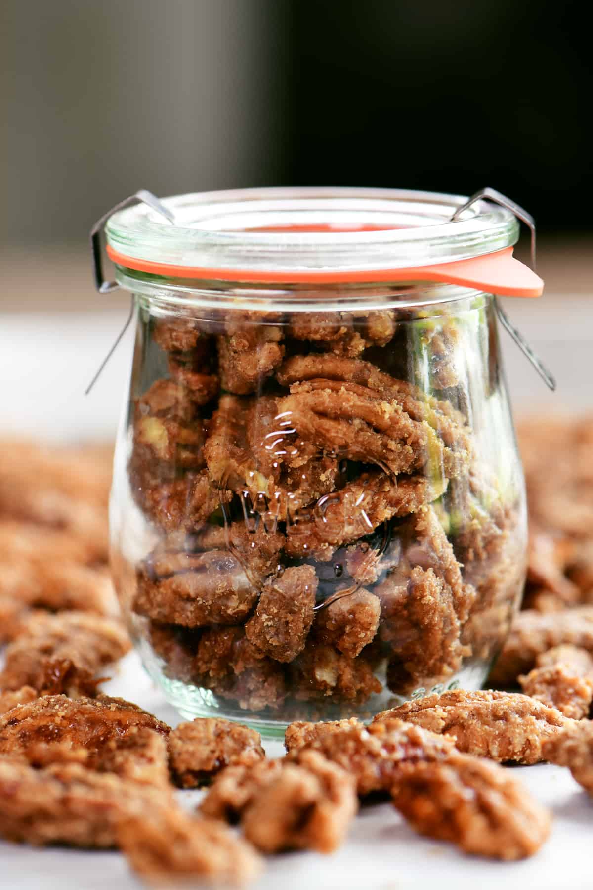 a jar with glazed pecans in it and around it.