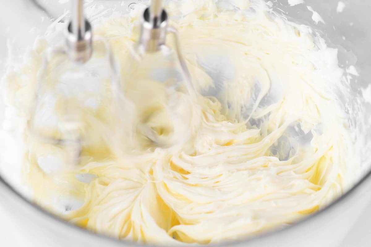 a mixer beating shortening and butter in a glass bowl.