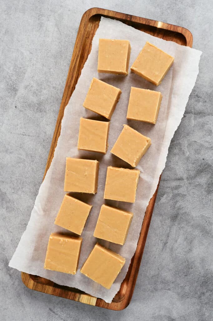 a dozen pieces of peanut butter fudge on a wooden serving tray.