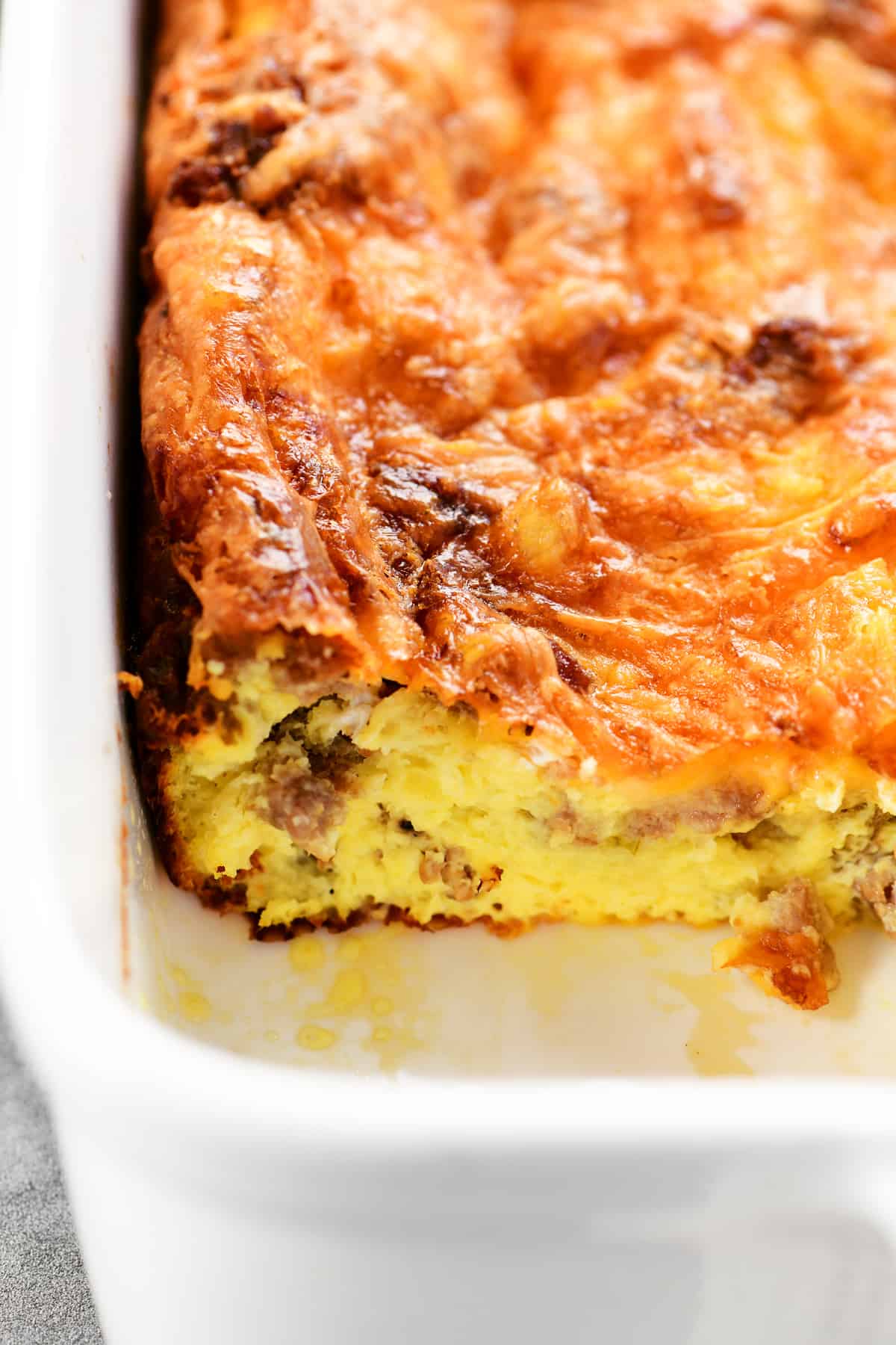 a sausage breakfast casserole in a baking dish with a single serving removed.