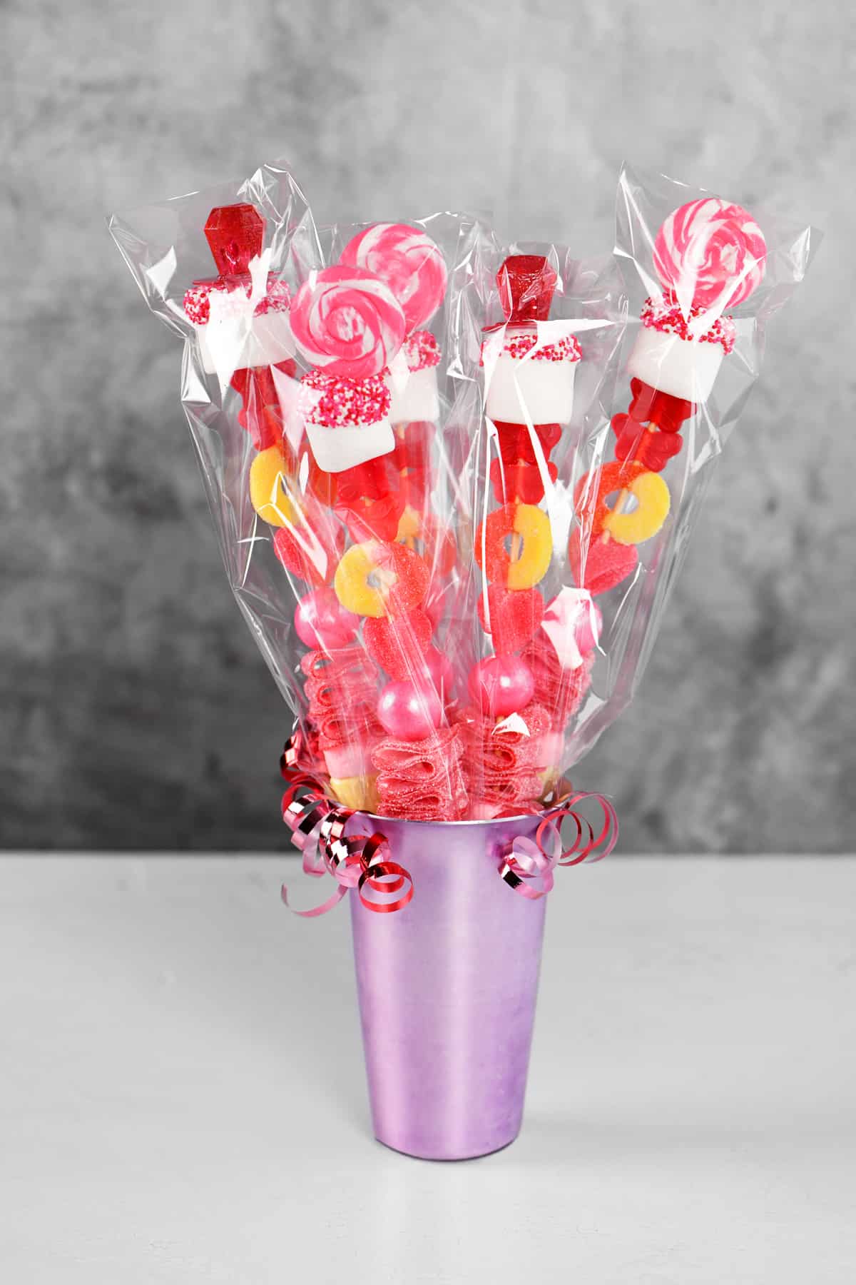 a lavender colored aluminum cup with candy sticks inside.