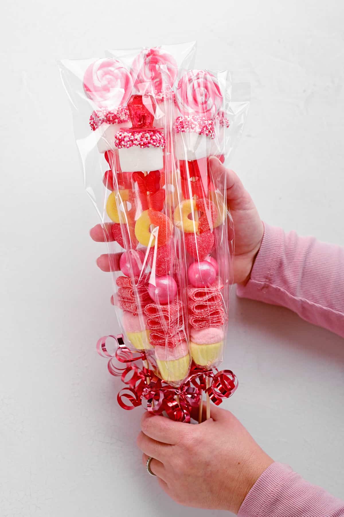 hands holding cellophane wrapped candy sticks.