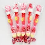 candy sticks wrapped in cellophane wrappers with red shiny ribbons.